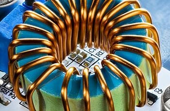 A close-up of a ferrite core coil with copper wire