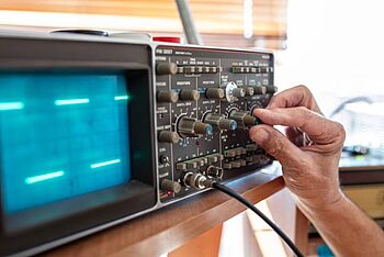 A technician adjusting an analog oscilloscope